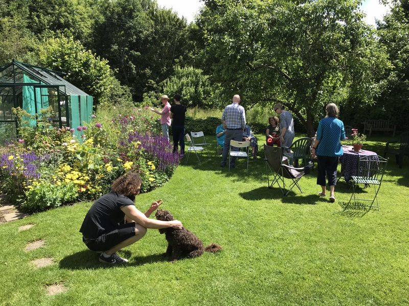 People strolling in garden, one playing with a dog