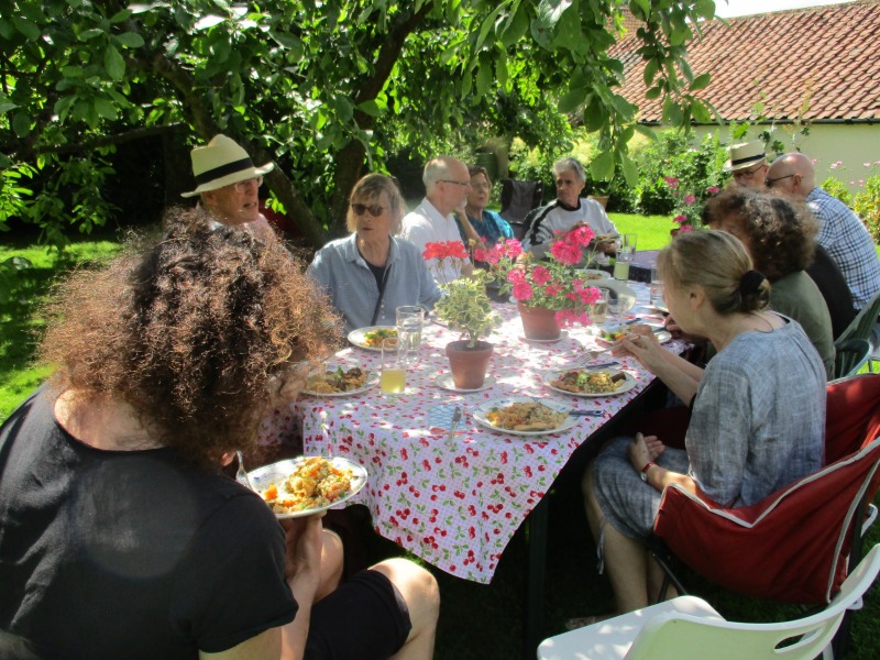 People eating round a table under a tree